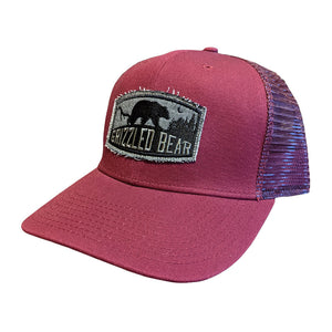 Front of a baseball cap with a pink colour front and purple back mesh. Black and grey vintage Grizzled Bear logo is on the front.